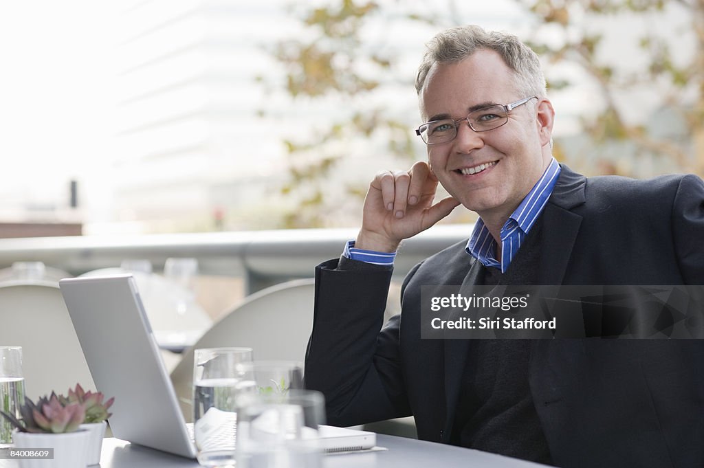 Smiling man sits in a cafe with a computer.