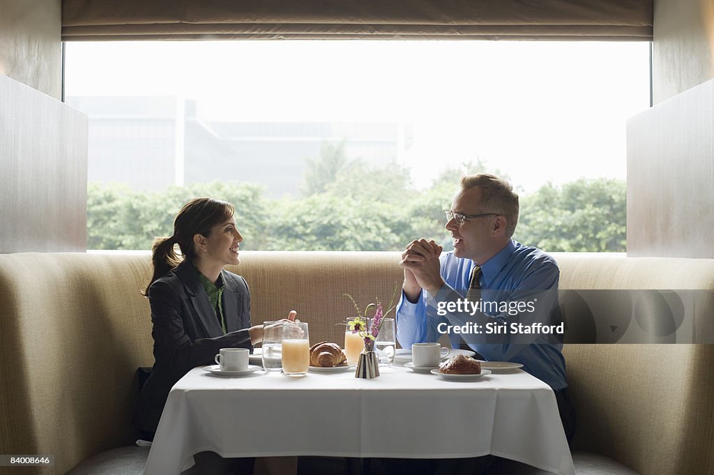 Two business people eat breakfast in restaurant.