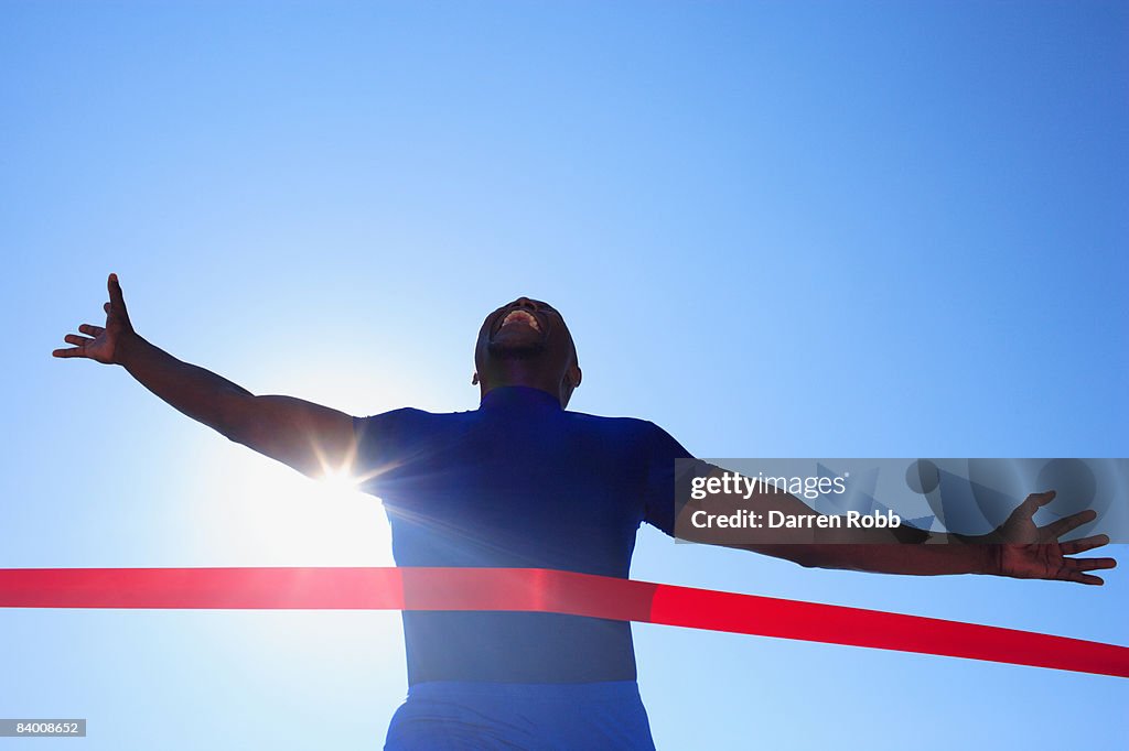Male runner crossing finishing line in race