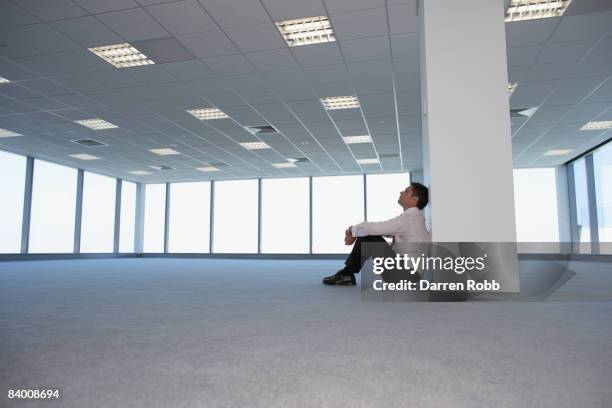 businessman sitting alone in an empty office - faillissement stockfoto's en -beelden