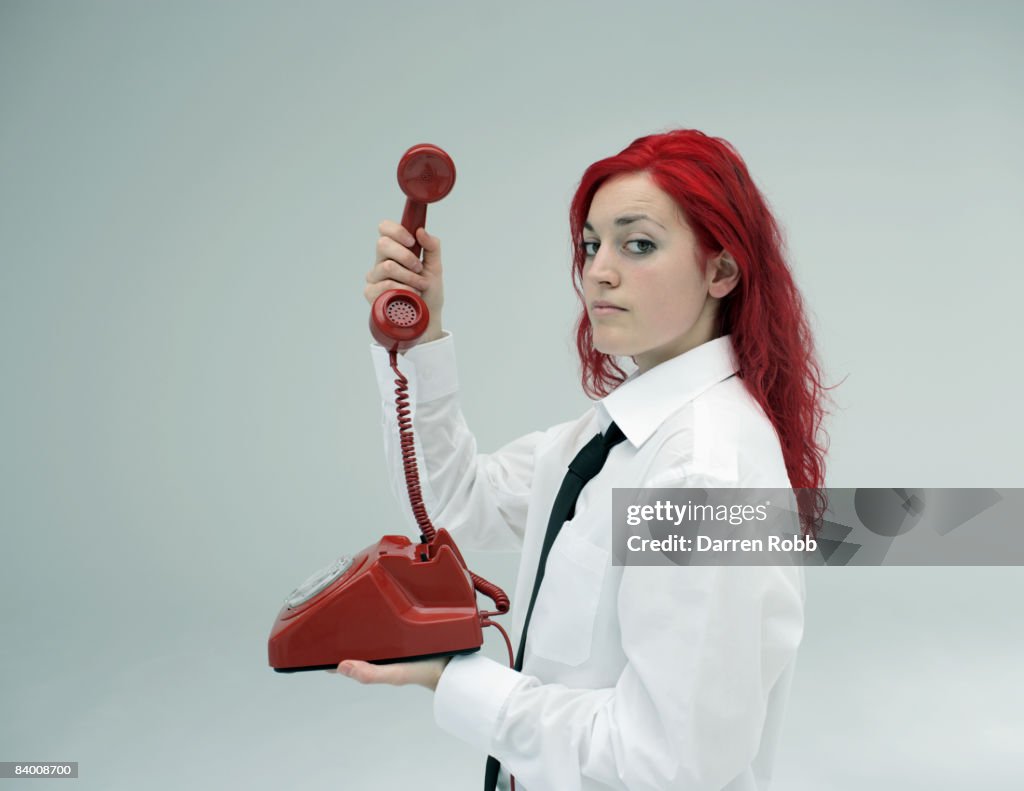 Businesswoman holding a red telehone and receiver