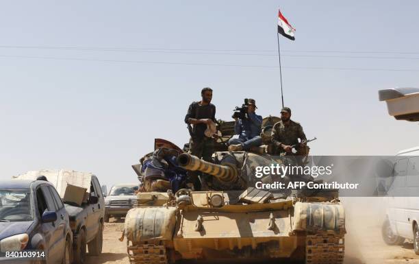 Syrian forces members sit on a tank waiting for vehicles to transport Islamic State group members in the Qara area in Syria's Qalamoun region on...