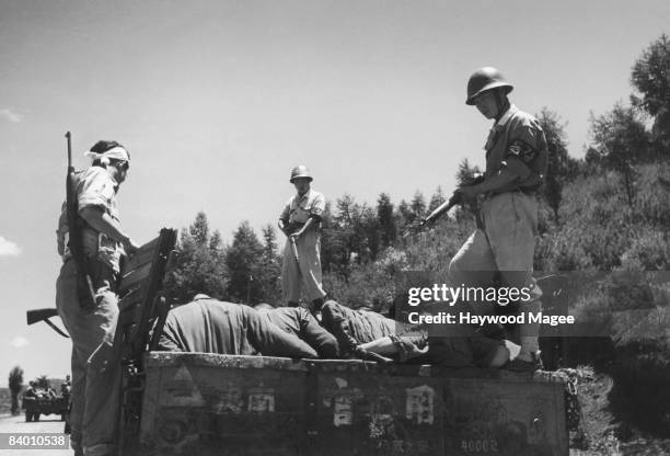 South Korean military policemen stand over a group of South-Korean prisoners, alleged to be communist sympathisers, on their way to execution for...