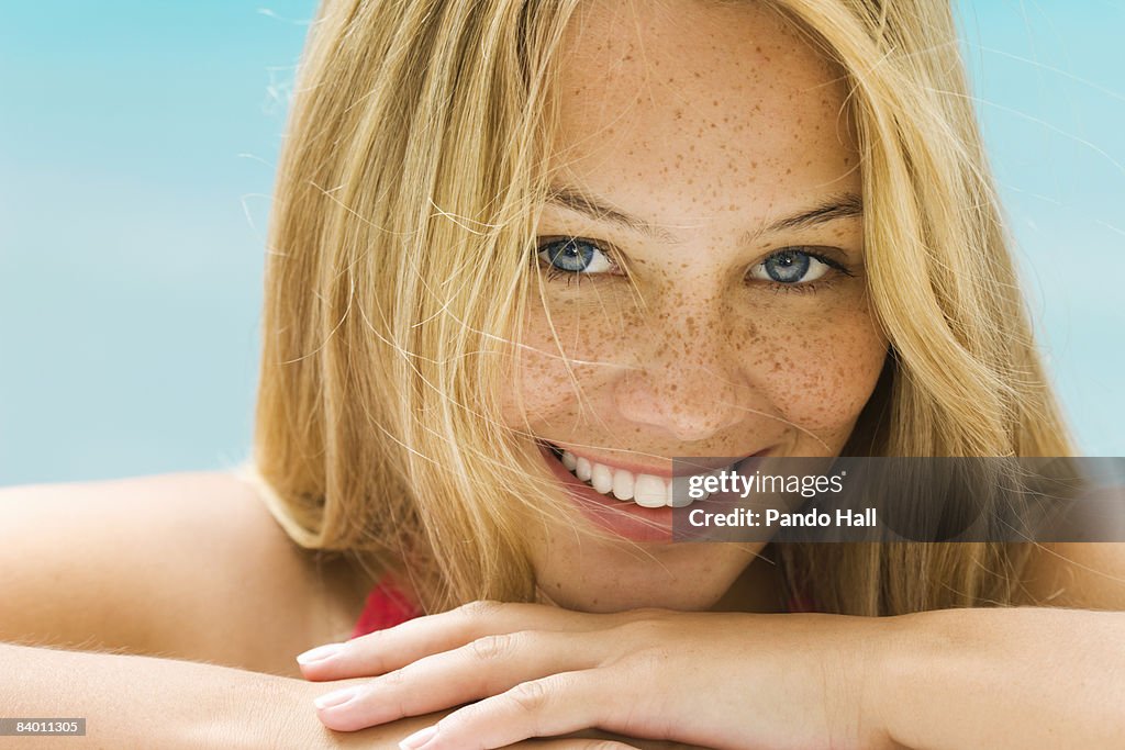 Young woman resting chin on arms, smiling