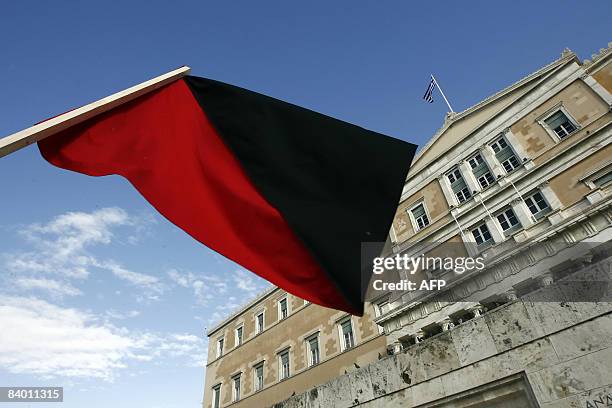 Red and black flag, used to denote anarchy, waves in front of the Greek Parliament during a demonstration in central Athens on December 12, 2008....