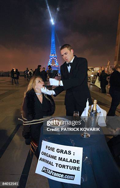 An activist from the organization People for the Ethical Treatment of Animals dressed up as a waiter force-feeds another member of the association,...