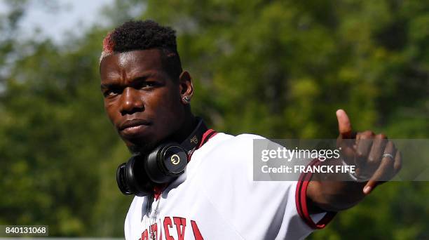 France's midfielder Paul Pogba gives the thumbs-up as he arrives at the French national football team training base in Clairefontaine on August 28 as...