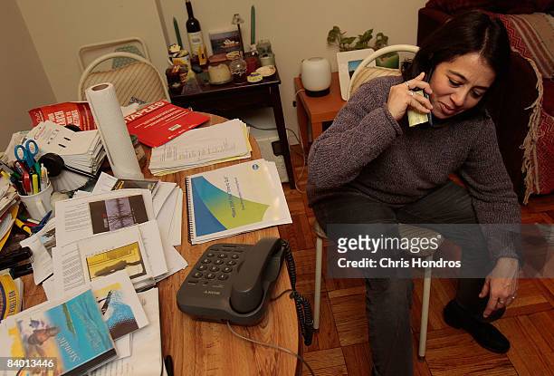 Jocelyn Taub, a job-hunting marketing professional, talks on the phone near her desk covered with resumes, job applications and other paperwork...