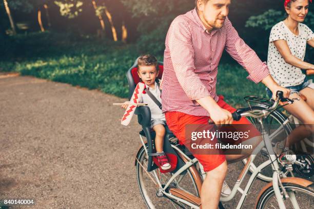 junge familie fahrrad im park - fahrradsattel stock-fotos und bilder