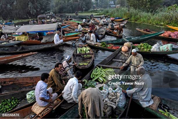 Kashmiri men gather with their boats laden with vegetables at the floating vegetable market on Dal Lake at dawn on August 28, 2017 in Srinagar, the...