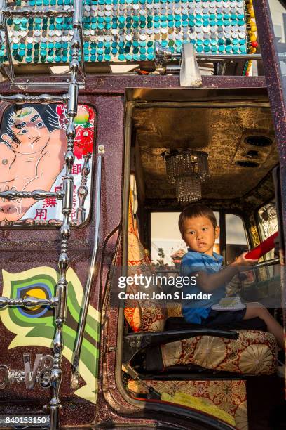 Child sits in the driver's seat of an Are dekotora Japanese decorated truck which are like long-haul discos and are works or art on wheels or perhaps...