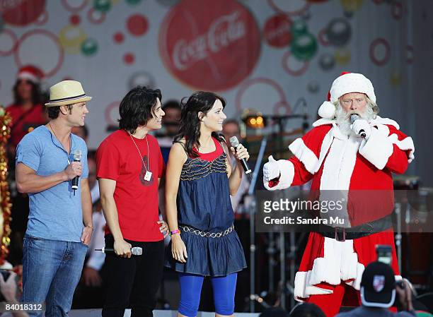 Santa performs live on stage with Sticky TV presenters Sam Wallace , Drew Neemia and Erin Simpson during Coca-Cola Christmas In The Park at Auckland...