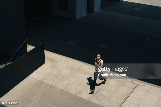 young woman running below building - running shadow stock-fotos und bilder