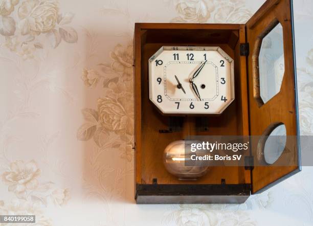 swinging pendulum of retro clock on the wall - pendulum stock pictures, royalty-free photos & images