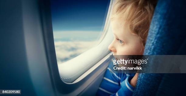 menino curioso, observando o céu da janela do avião - vehicle seat - fotografias e filmes do acervo