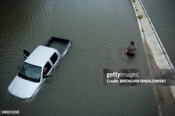 Truck driver walks past an abandoned truck while checking the depth of an underpass during the aftermath of Hurricane Harvey August 28, 2017 in...