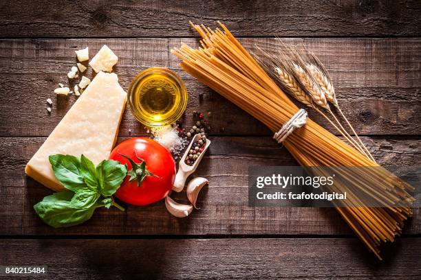 volkoren spaghetti met ingrediënten op rustieke houten tafel - pasta tomato basil stockfoto's en -beelden