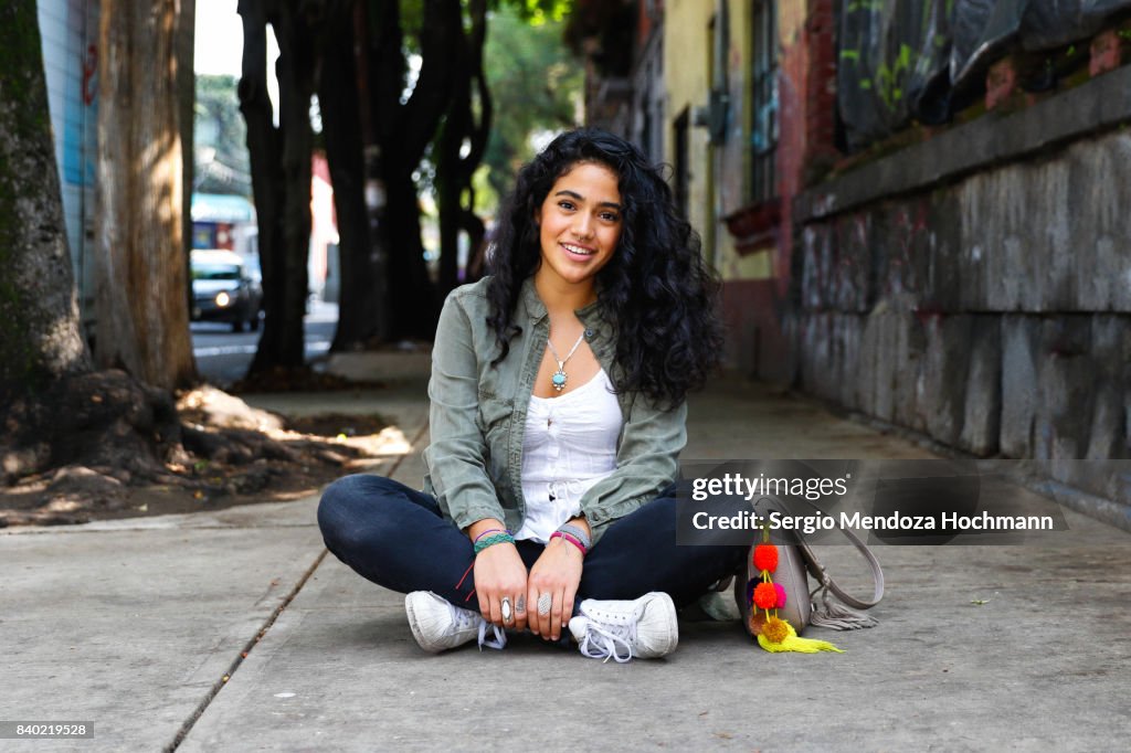 One young Hispanic woman sitting crossed-legged on a sidewalk in Mexico City