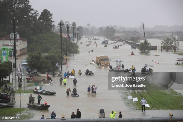 People walk down a flooded street as they evacuate their homes after the area was inundated with flooding from Hurricane Harvey on August 28, 2017 in...