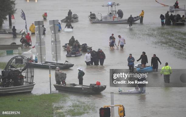 People walk down a flooded street as they evacuate their homes after the area was inundated with flooding from Hurricane Harvey on August 28, 2017 in...