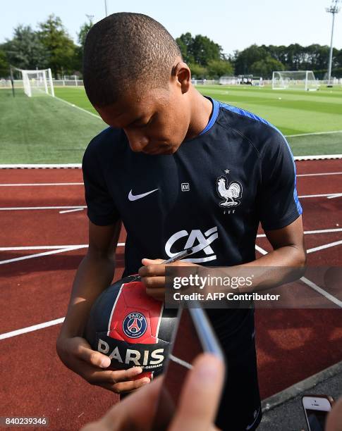 France's forward Kylian Mbappe signs autographs before a training session in Clairefontaine en Yvelines on August 28 as part of the team's...