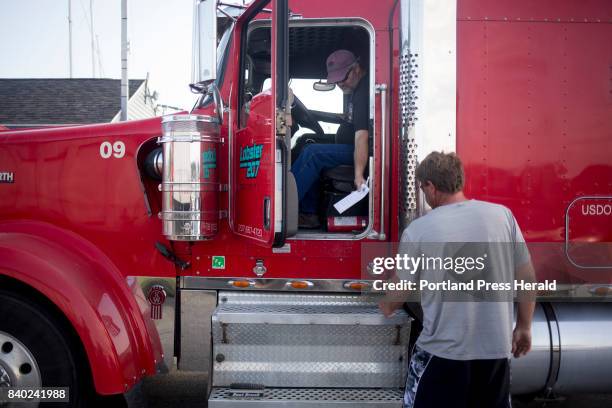 Dwayne Bradford, a union driver, hands Mike Gale, the manager of Fox Island Lobstering, paperwork to sign after loading union-caught lobster from...