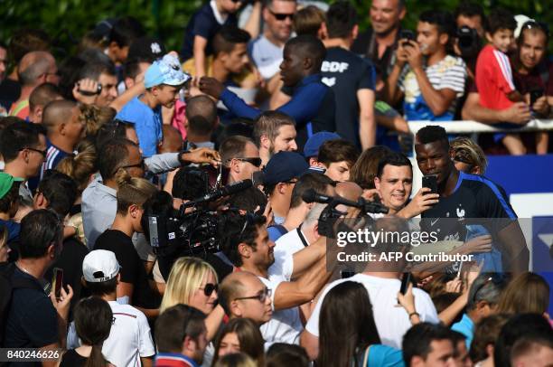 France's midfielder Paul Pogba poses with fans during a training session in Clairefontaine en Yvelines on August 28 as part of the team's preparation...