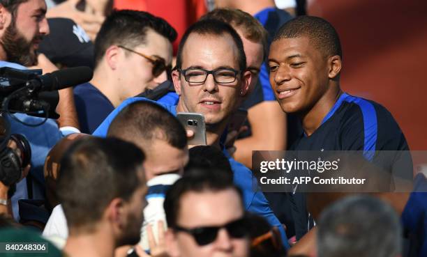 France's forward Kylian Mbappe poses with fans during a training session in Clairefontaine en Yvelines on August 28 as part of the team's preparation...