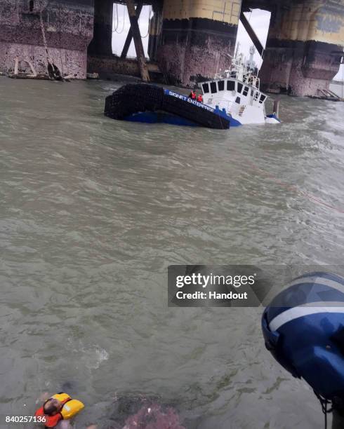 In this handout provided by the U.S. Coast Guard, the Signet Enterprise is sinking as helicopter aircrew assists the people in distress in the water...