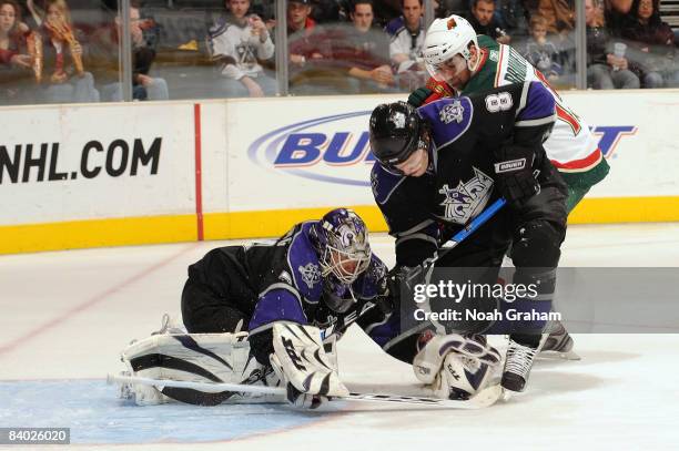 Andrew Brunette of the Minnesota Wild fights for the puck outside the crease against Erik Ersberg and Drew Doughty of the Los Angeles Kings on...