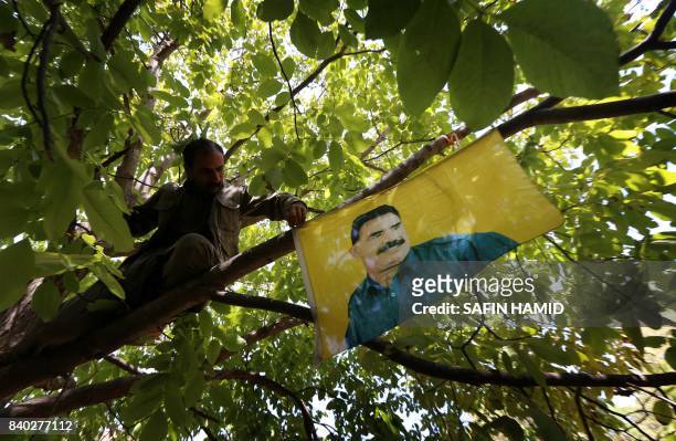 Members of the anti-Iranian group, Kurdistan Free Life Party , hang up a flag of jailed Kurdistan Workers' Party leader, Abdullah Ocalan, at their...