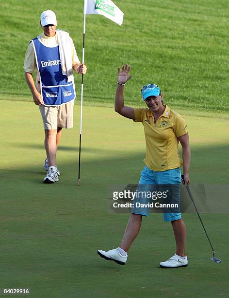 Annika Sorenstam of Sweden waves to the crowd as her caddie Terry McNamara acknowledges his player scoring a final birdie at the 18th hole during her...