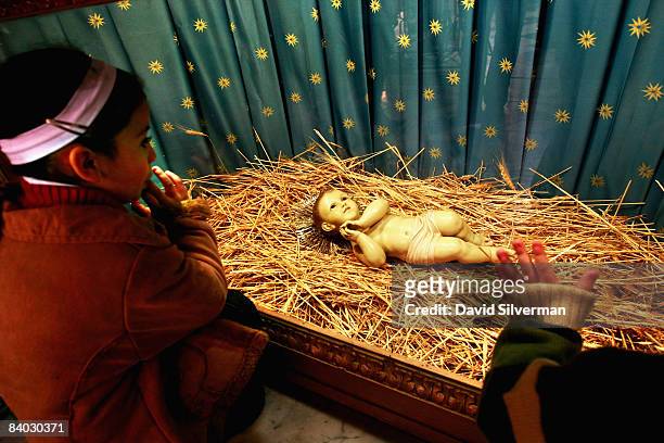 Palestinian Christian children Adrianne Khader and her brother Issa Khader pray in front of the doll representing the infant Jesus in St. Catherine's...