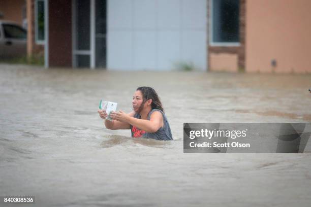 People make their way out of a flooded neighborhood after it was inundated with rain water, remnants of Hurricane Harvey, on August 28, 2017 in...