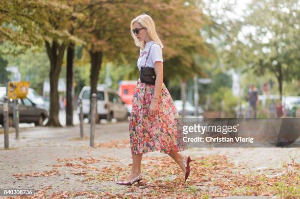 Sonia Lyson wearing a midi skirt with floral print Ganni, a white T-shirt with the print Love Dog from Ganni, a black Chanel vintage bag, vintage...