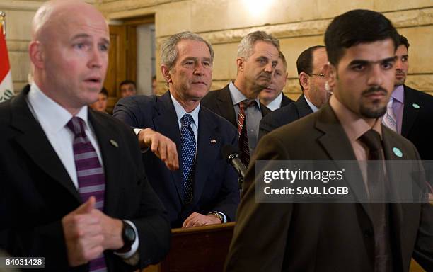 President George W. Bush , surrounded by security personnel, gestures alongside Iraq's Prime Minister Nuri al-Maliki after an Iraqi man threw his...