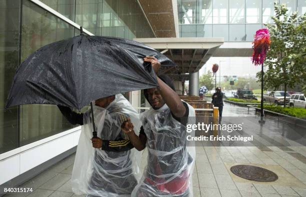 Evacuees fight the rain outside the George Brown Convention Center which has been turned into a shelter run by the American Red Cross to house...