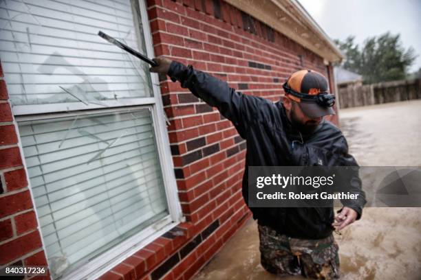 Jan Tullos from College Station, smashes the window on a flooded home in an attempt to rescue a woman reportedly stuck inside with a broken leg....