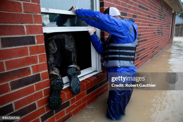 Rescue volunteer Jan Tullos climbs through a window as Steven Andersen helps in search of an injured woman who was reportedly stranded inside this...