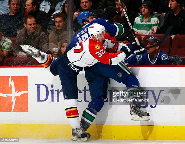 Ryan Kesler of the Vancouver Canucks is checked into the boards by Michal Rapik of the Florida Panthers during their game at General Motors Place on...
