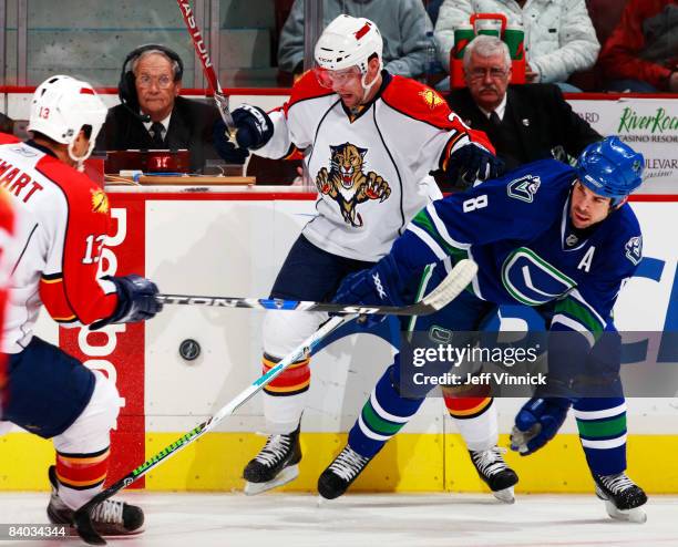 Willie Mitchell of the Vancouver Canucks and Keith Ballard of the Florida Panthers battle for the puck during their game at General Motors Place on...