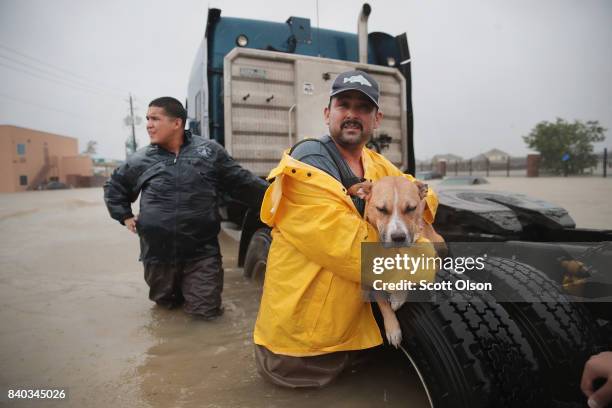 People make their way out of a flooded neighborhood after it was inundated with rain water, remnants of Hurricane Harvey, on August 28, 2017 in...