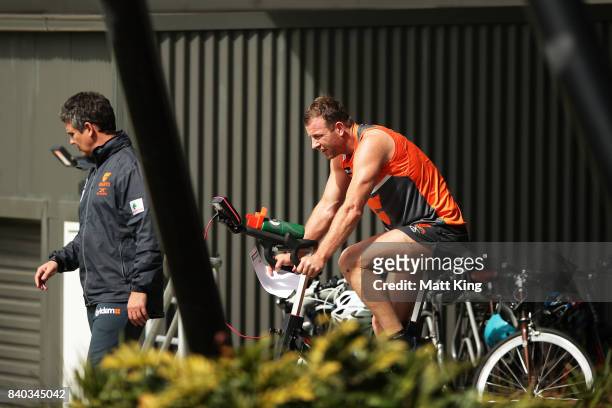 Steve Johnson of the Giants rides a bike as Giants head coach Leon Cameron looks on during a Greater Western Sydney Giants AFL training session at...