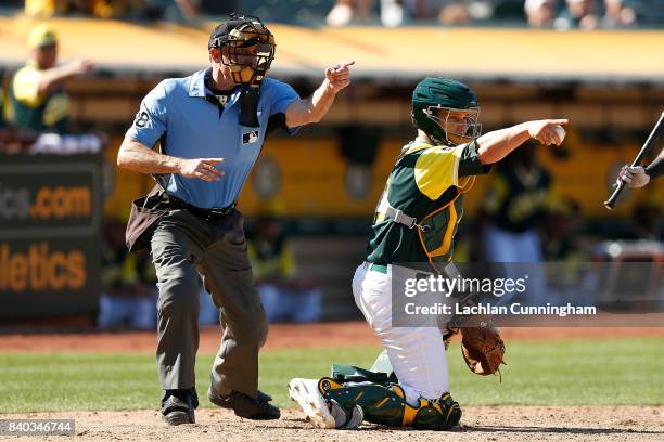 Catcher Dustin Garneau of the Oakland Athletics and home plate umpire Dan Iassogna look to the first base umpire for a decision in the ninth inning...