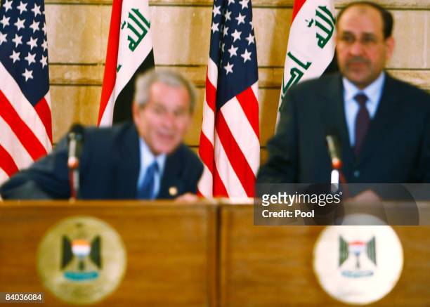 President George W. Bush ducks as an Iraqi man throws his shoes at the President during a joint press conference with Iraq's Prime Minister Nuri...