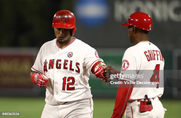 Martin Maldonado of the Los Angeles Angels of Anaheim gets a fist bump from first base coach infield coach Alfredo Griffin after Maldonado singled to...