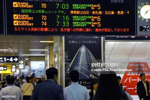 Commuters look up a monitor displaying the delay of train due to North Korea's missile launch over Hokkaido at JR Sapporo Station on August 29, 2017...