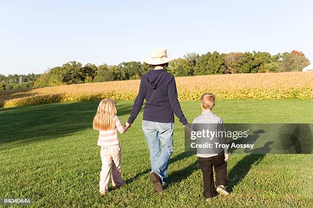 grandmother walking away with grandchildren - troy bond stock pictures, royalty-free photos & images