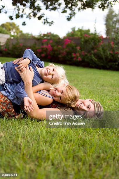 children laying on top of their mother outdoors - troy bond stock pictures, royalty-free photos & images