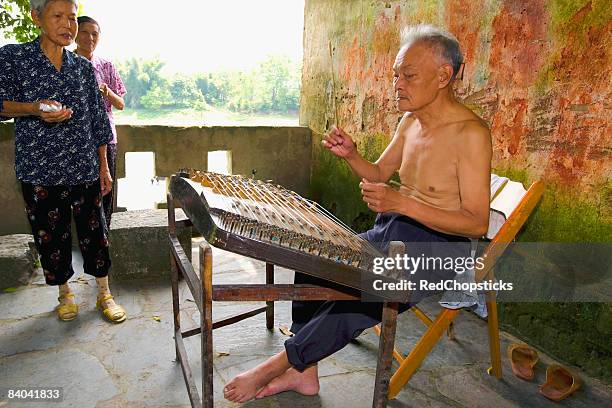 senior man playing hammered dulcimer with his family standing beside him, fuli village, yangshuo, guangxi province, china - saltério instrumento de corda - fotografias e filmes do acervo
